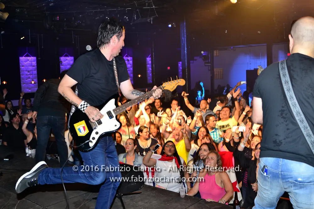 Guitarist performing beside an enthusiastic crowd